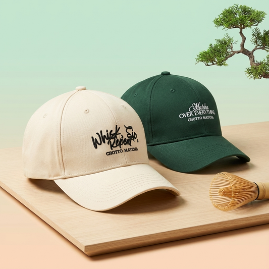 Two baseball caps, one beige and one green, with text on a wooden surface and light green background.